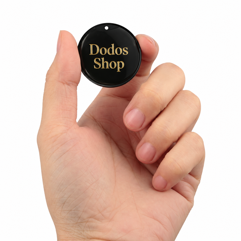 GPS Pet Tracker
A hand holding a small round black tag with gold lettering that reads 'Dodos Shop' against a plain white background.