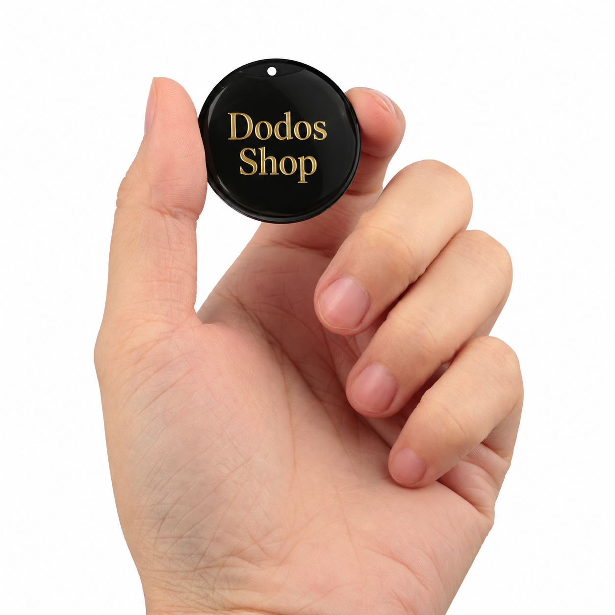 GPS Pet Tracker
A hand holding a small round black tag with gold lettering that reads 'Dodos Shop' against a plain white background.