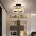 Luxury Crystal Lamp
A modern semi-flush mount crystal chandelier light fixture with a black ceiling mount and clear hanging crystal prisms, shown illuminated in a showroom setting with a 'Dodos Shop' logo on the wall behind it.