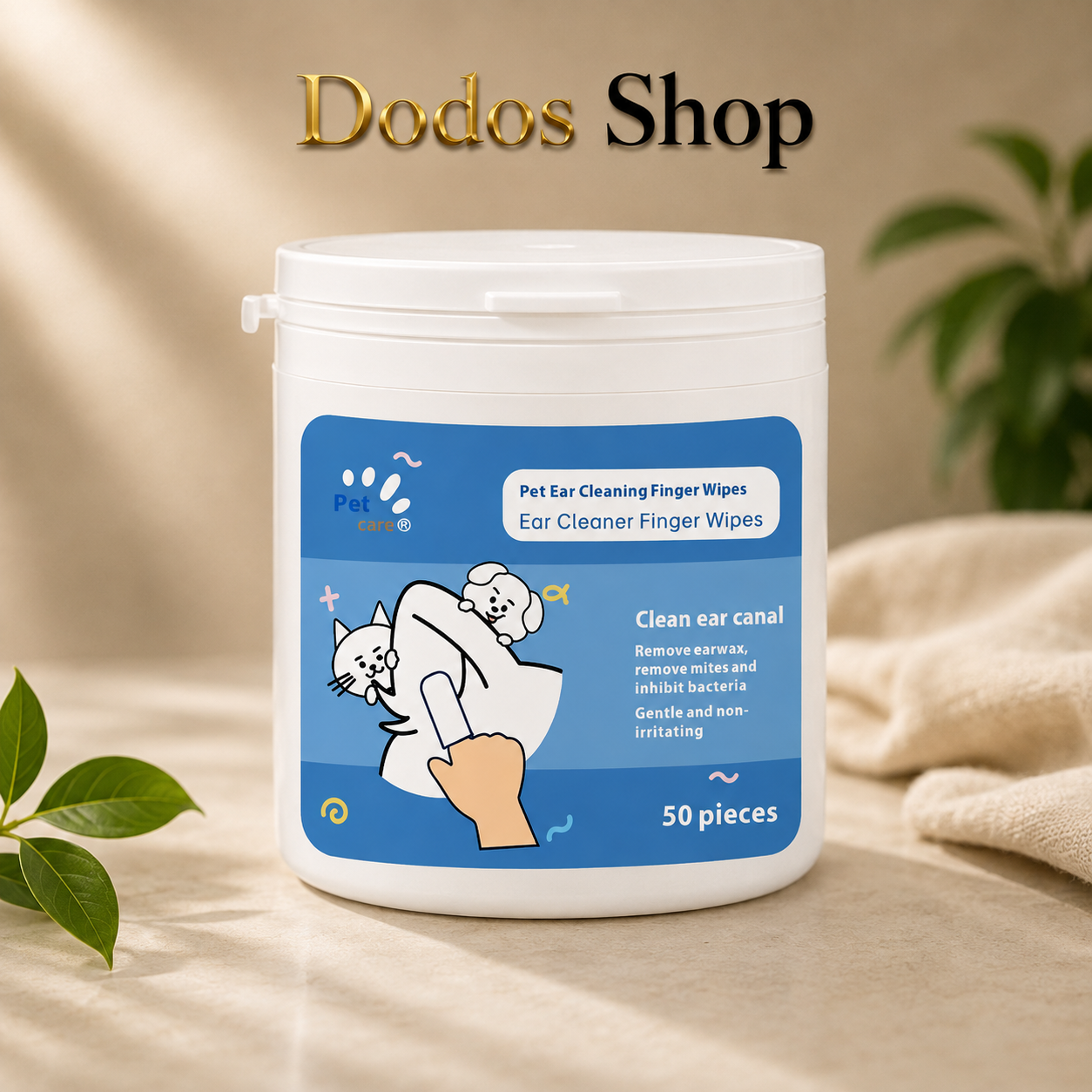 A white plastic tub of Dodos Shop Pet Ear Cleaning Finger Wipes with a blue label, set on a beige fabric surface with soft-focus green leaves in the background.