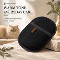 A black textured grooming mitt with a small brown leather tab, displayed on a stone block in a warm, softly lit setting with a cat in the background and promotional text on the left.