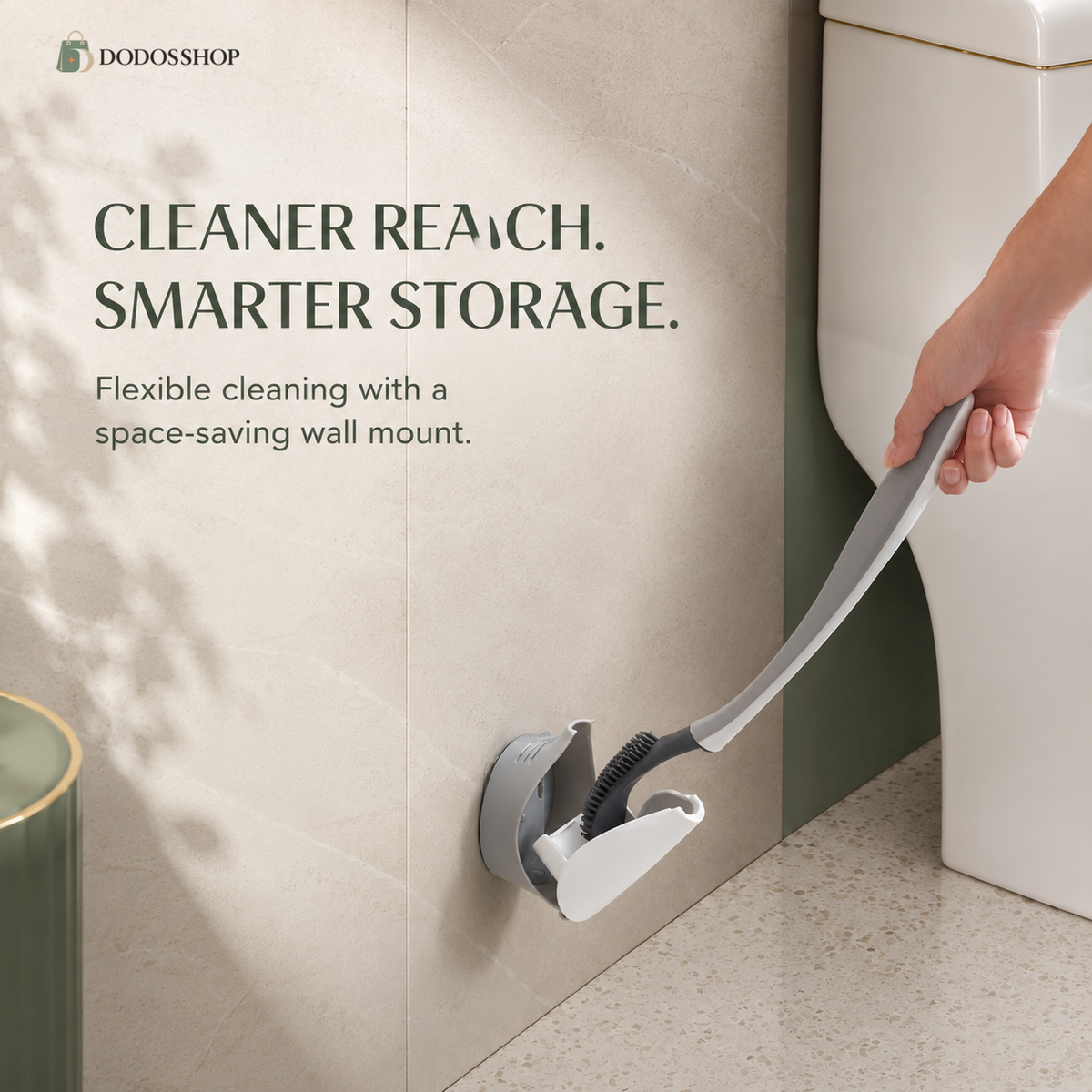 A wall-mounted flexible cleaning brush holder on a beige tiled bathroom wall, with a hand holding the attached flexible brush. Text on the image reads 'CLEANER REACH.